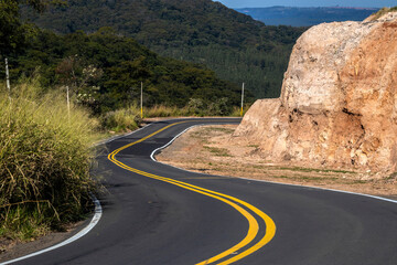 View of an empty paved rural road, flanked by Atlantic forest and eucalyptus fields in a mountain range in Brazil