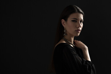 An elegant, dressed-up woman showcasing a silver necklace and earrings, wearing a stylish black dress. Perfect for themes of fashion, elegance, and beauty.