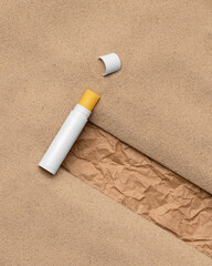 Lip yellow balm with cap on sand. Natural hygienic lipstick on beach packaging mock-up. Lip care cosmetics. Copy space. Zero waste concept. Top view
