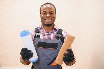 African American plumber holding new and used water filters - Powered by Adobe