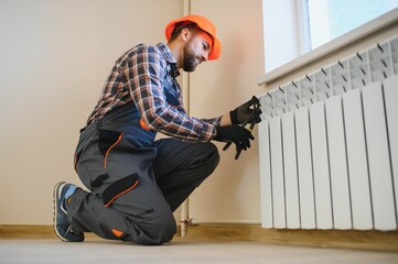 Plumber man is blocking repairs radiators of heating battery in apartment tap