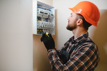 handsome young man electrician working on switchboard of house building construction site