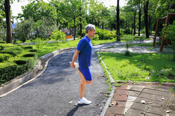 Senior Asian man is stretching his leg muscle during warm up exercise work out in the morning at public park for healthy and longevity concept