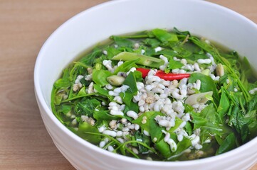 Sweet vegetable curry with red ant eggs Local food on white bowl on brown wooden table