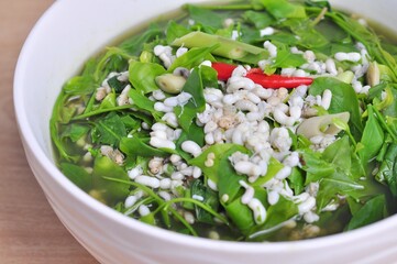 Sweet vegetable curry with red ant eggs Local food on white bowl on brown wooden table