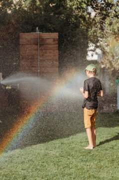 Two brothers playing with water in a backyard on a sunny day