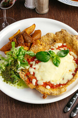 pork schnitzel with sauce and vegetables on a plate. restaurant