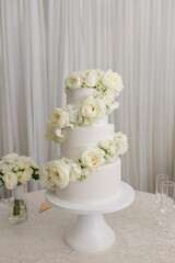 White tiered wedding cake with white roses
