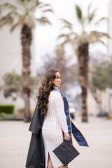 Graduate looking over her shoulder with palm trees in the backgr