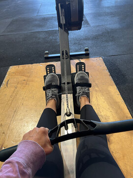 Person using a rowing machine in a gym, view from above.