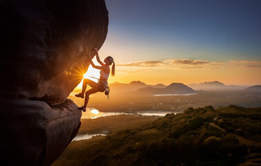 Eine Frau klettert in der Abendsonne an einem Felsvorsprung