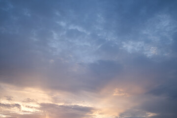 Soft blue sky combines with light of sunset to create a peaceful sky. Beautiful landscape with clouds and orange sun.