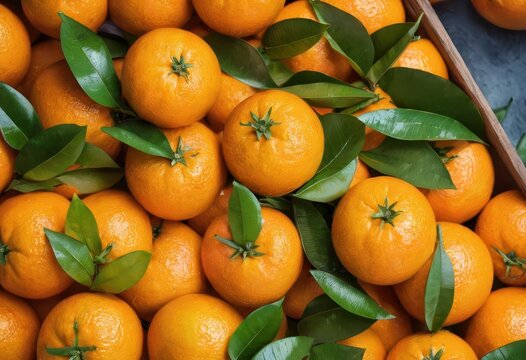 A close-up of a pile of oranges with green leaves.