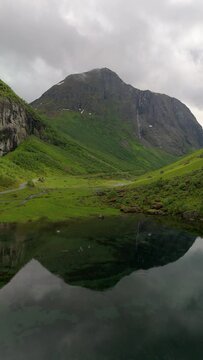 A serene scene of a mountain reflected in a tranquil lake surrounded by other mountains, creating a stunning mirror image. Norweigan Fjords Stavbergvatnet Urke