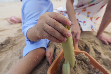 Close up of hand of asian young boy and mother playing sand and toy on beach