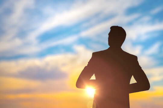 Man silhouette standing confidently businessman, vibrant sunset sky, contemplating life under colorful clouds