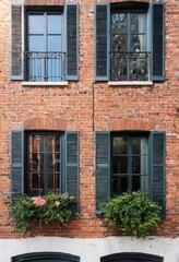 Obraz premium Brick building with green shutters and flowers.