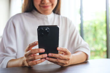 Closeup image of a woman holding and using mobile phone