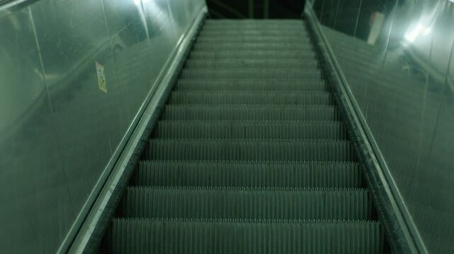Empty escalator in a quiet, dimly lit metro station, conveying a sense of stillness and urban solitude, reflective surfaces