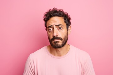 Fototapeta premium Sad man, 35, Middle Eastern, feeling isolated, on a pastel light pink background