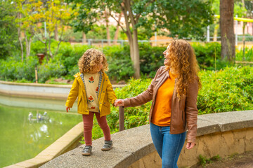 Fototapeta premium Girl walking on rail holding the hand of her mother