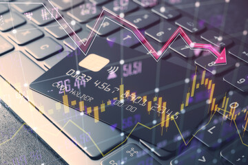 Close up of keyboard and bank cards with glowing falling forex chart and index grid on blurry background. Crisis and financial recession concept. Double exposure.
