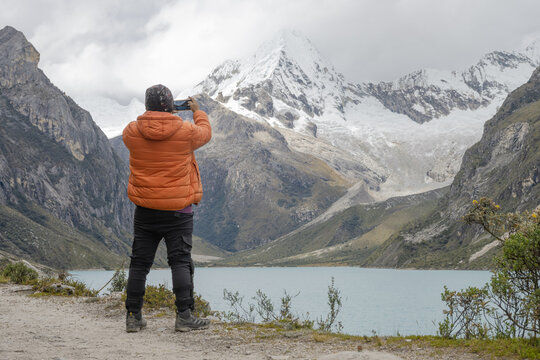 Man is taking photo with a mobile phone in the snowy mountains