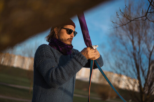 Man sets a slackline in the city park.