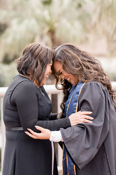 Mother and daughter laughing together while touching heads in gr