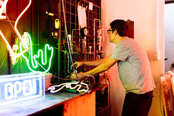 Man Filling Neon Sign With Gas at a Workshop