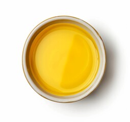 Top view of yellow liquid in a petri dish or glass with bubbles on a white background.