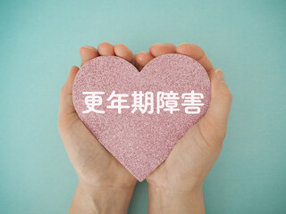 手に持ったハートに更年期障害の文字