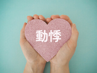 手に持ったハートに動悸の文字