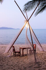 Romantic beach dining under a tent with an ocean view, ideal for a sunset meal by the sea