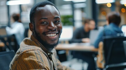 Fototapeta premium A man smiles at the camera while sitting at his desk in a modern office