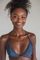 Radiant young woman in a sleek swimsuit, standing confidently with a bright smile, against a white backdrop