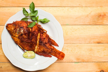 fried fish dish in a plate on a wooden table