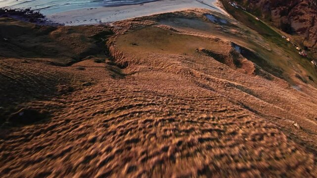 FPV fly down mountain slope during golden hour in Hoddevik, Norway