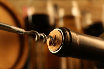 Wine bottle with corkscrew on blurred background, closeup