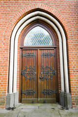 Old door of a European church with a round arch. Antique entrance made of wood and metal decorations.
