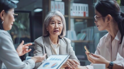 Three women in a meeting, discussing data on a tablet
