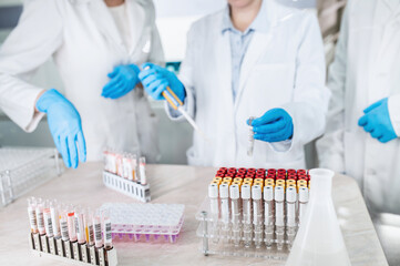 A group of people in medical gowns and disposable gloves conducts research in a modern bio laboratory. Doctors in the laboratory do tests. Unrecognizable	