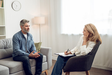 Man sitting on couch in counseling office and complaining about his troubles to female psychologist