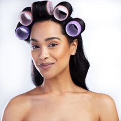 Beauty portrait, woman and rollers in hair for curly style with salon aesthetic and texture maintenance in studio. Model smile, female person and curlers for hairstyle results by white background