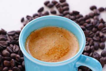 エスプレッソに牛乳をたっぷり入れたコーヒー、カフェ・ラッテと、深煎りしたコーヒー豆
