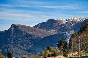 Mountains with little snow on the summit in the fjord in Norway. Meadow, house, trees