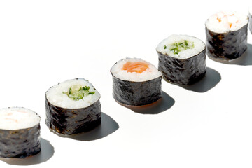 Various maki rolls with shrimp, salmon, cucumber on a white background with hard shadows