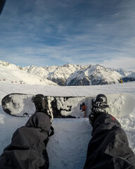 POV of a snowboarder sitting on a slope looking down the mountain 