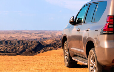 Close-up of a vehicle in the sand in  front a cliff