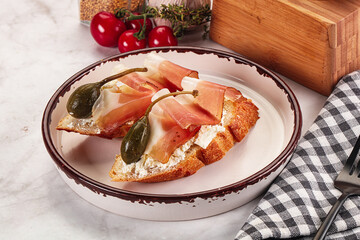 Bruschetta with jamon and caper berries